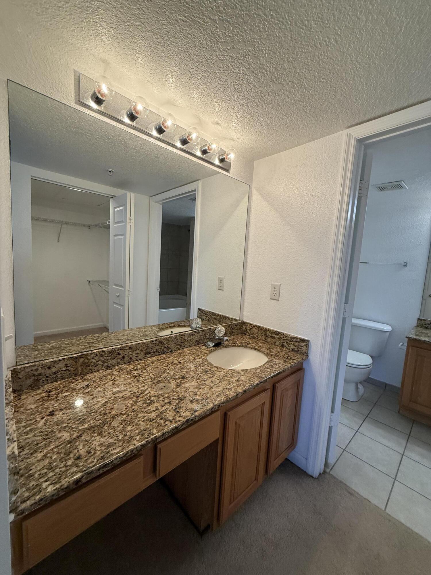301 Southwest Palm Drive, Unit 305 Port St. Lucie, FL 34986 - Photo 9 of 17 a bathroom with a granite countertop sink and a mirror