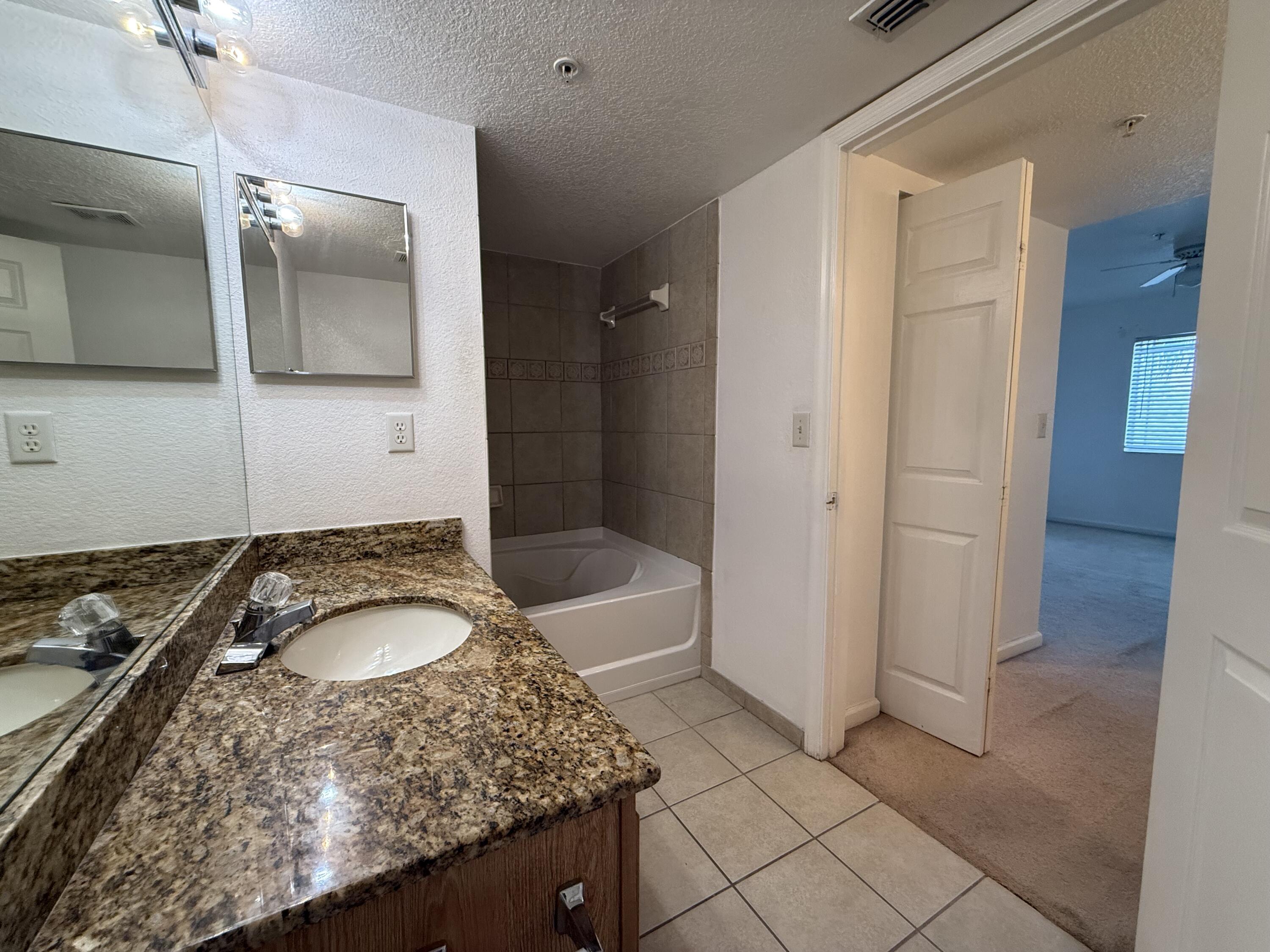 301 Southwest Palm Drive, Unit 305 Port St. Lucie, FL 34986 - Photo 10 of 17 a bathroom with a granite countertop sink and a mirror