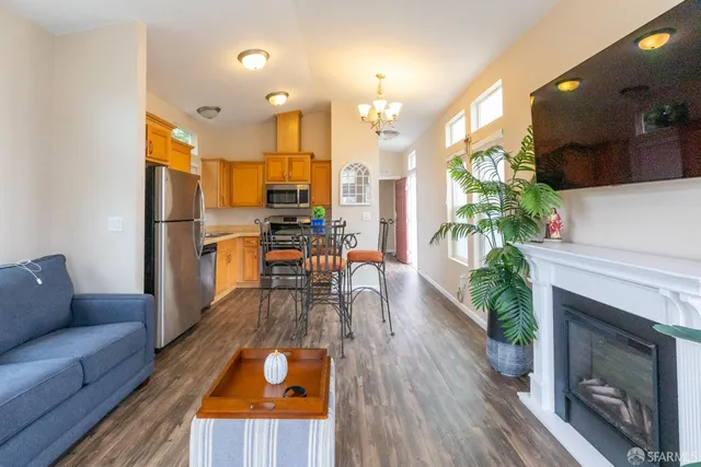 a open kitchen with stainless steel appliances granite countertop a stove top oven a refrigerator a dining table and chairs with wooden floor