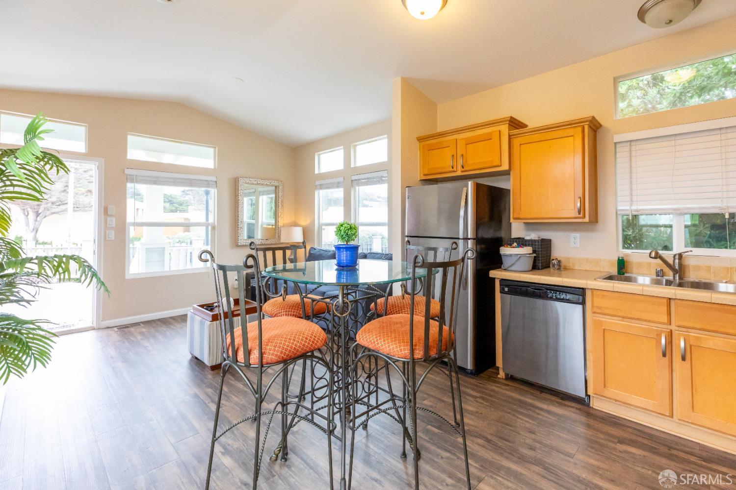 125 1st Avenue Pacifica, CA 94044 - Photo 13 of 55 a open kitchen with stainless steel appliances granite countertop a stove top oven a refrigerator a dining table and chairs with wooden floor