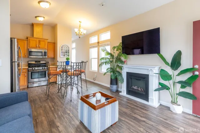 a kitchen with stainless steel appliances granite countertop a stove a sink dishwasher a microwave oven and a dining table with wooden floor