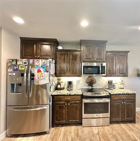 a kitchen with stainless steel appliances granite countertop a stove a refrigerator and a sink