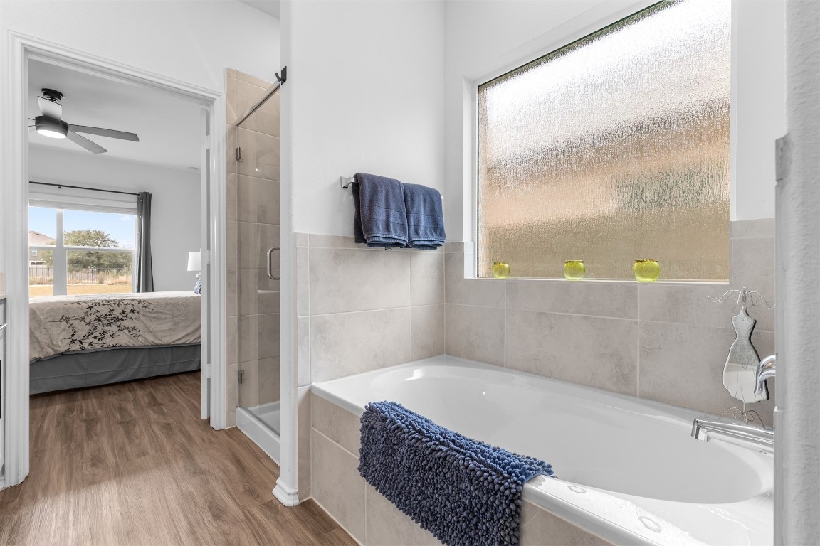 432 Clear Springs Road Georgetown, TX 78628 - Photo 8 of 27 Ensuite bathroom with a bath, a shower stall, healthy amount of natural light, and wood finished floors