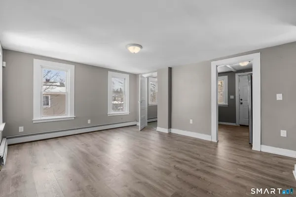 an empty room with wooden floor and windows