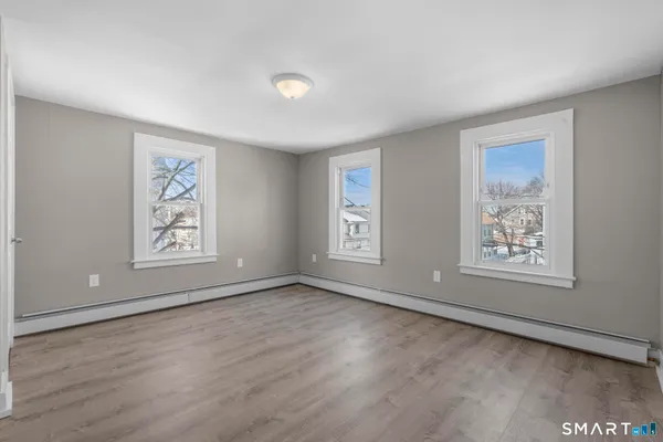 a view of an empty room with a window and wooden floor