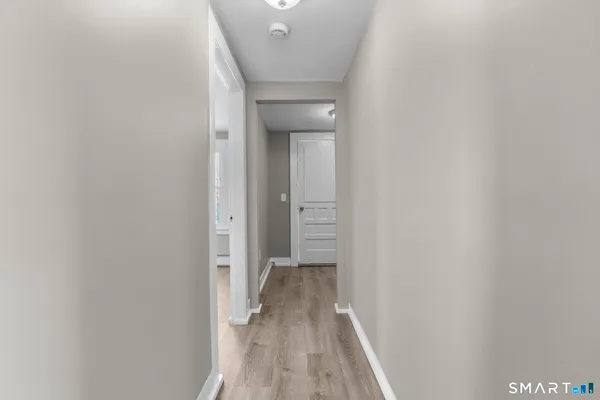 a view of a hallway with wooden floor and a bathroom