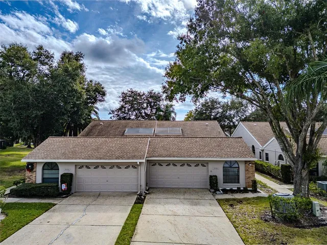 a view of a white house next to a yard with plants and trees