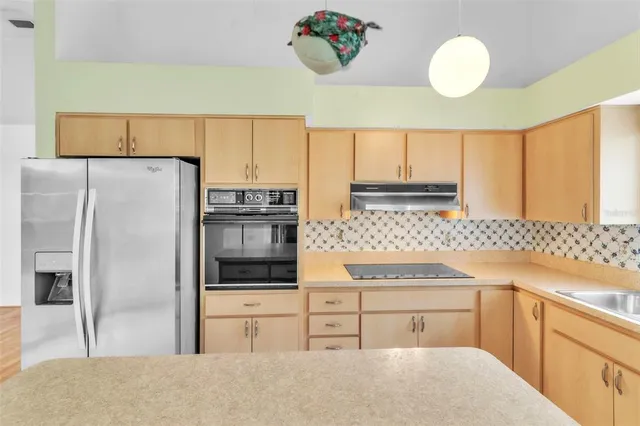 a kitchen with a sink a stove and chairs with white walls
