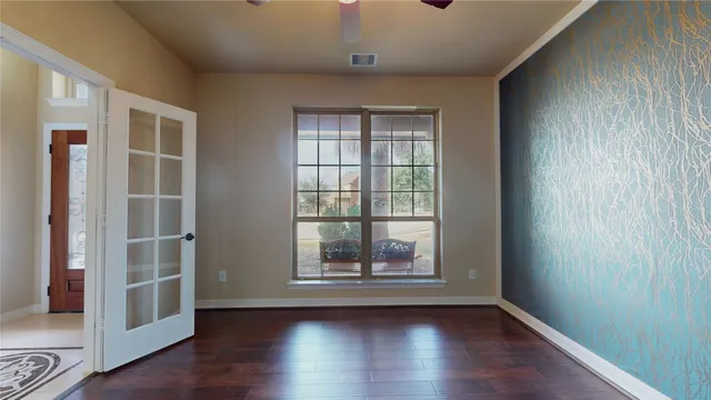 an empty room with wooden floor and windows