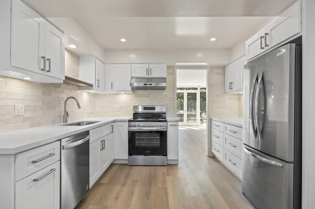 a kitchen with white cabinets stainless steel appliances and a sink