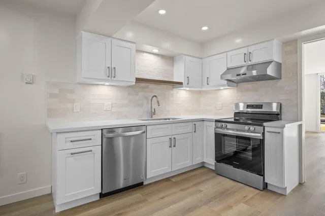 a kitchen with stainless steel appliances granite countertop a stove and white cabinets
