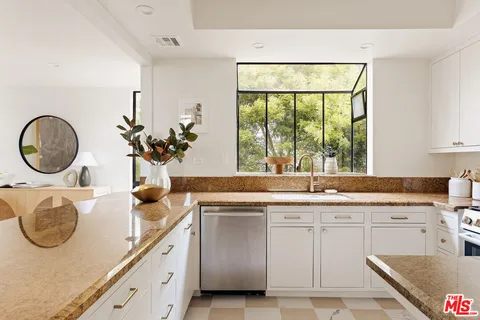 a kitchen with kitchen island granite countertop a sink a stove and a window