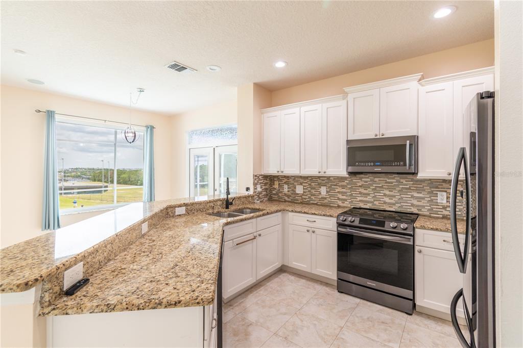 3862 Beacon Ridge Way Clermont, FL 34711 - Photo 29 of 56 a kitchen with granite countertop a stove sink and refrigerator