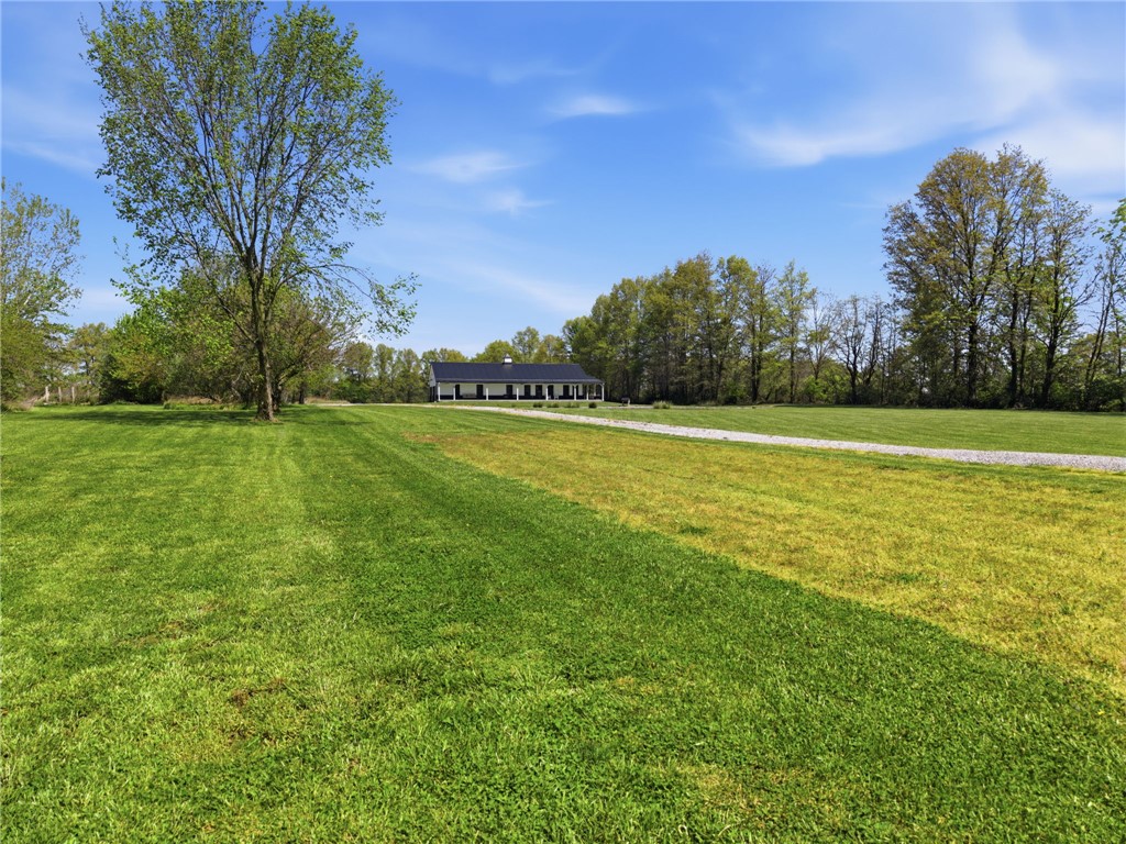 1602 Westboro Road Blanchester, OH 45107 - Photo 66 of 81 Expansive green grounds unfold towards a distant modern farmhouse, framed by lush trees and clear skies.