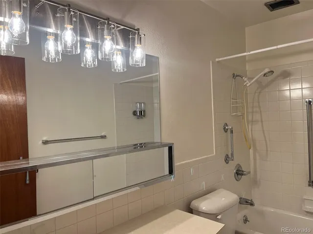 a bathroom with a granite countertop sink a toilet and shower