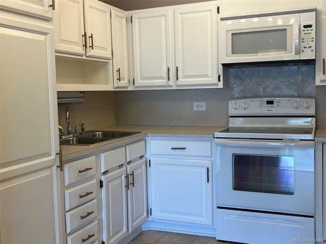 a kitchen with white cabinets and white appliances