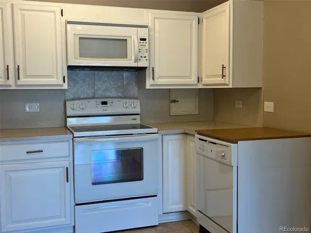 a kitchen with granite countertop white cabinets and white appliances