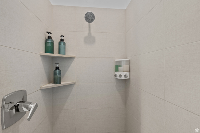 1122 South 1790th West, Unit 1 St. George, UT 84770 - Photo 28 of 37 Shower enclosure featuring light-toned rectangular wall tiling, a chrome shower head, a chrome single-handle faucet, and two integrated corner shelves