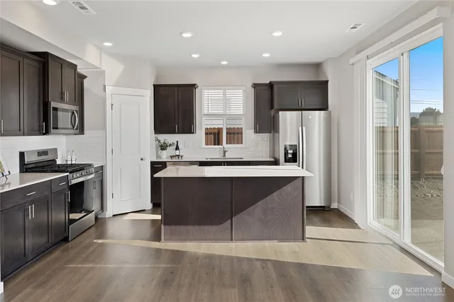 a large kitchen with stainless steel appliances kitchen island granite countertop a refrigerator and a stove top oven