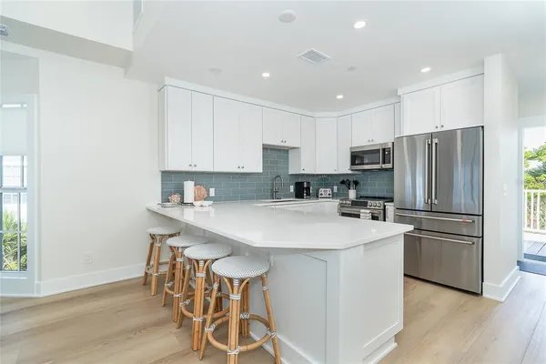 a kitchen with stainless steel appliances a table chairs refrigerator and wooden floor