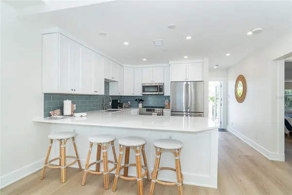 a kitchen with stainless steel appliances granite countertop a table chairs sink and cabinets