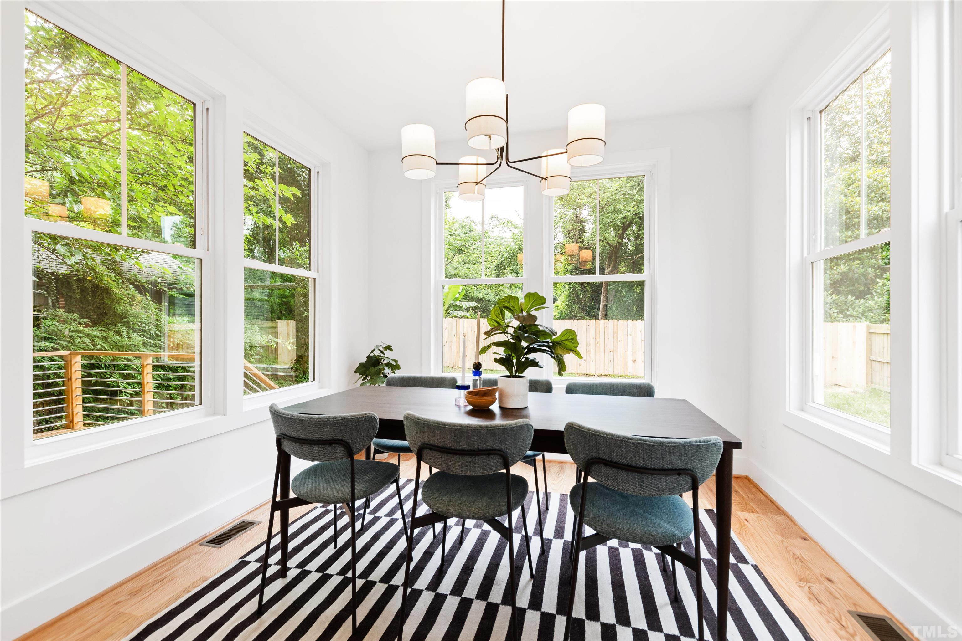 704 Colonial Street Durham, NC 27701 - Photo 17 of 42 a dining room with wooden floor a chandelier a glass table and chairs
