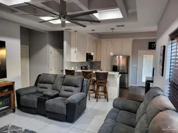 a living room with furniture a refrigerator and a flat screen tv