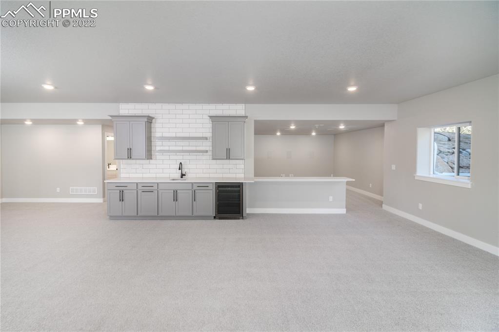10675 Hardy Road Colorado Springs, CO 80908 - Photo 22 of 45 a large white kitchen with kitchen island a sink stainless steel appliances and cabinets