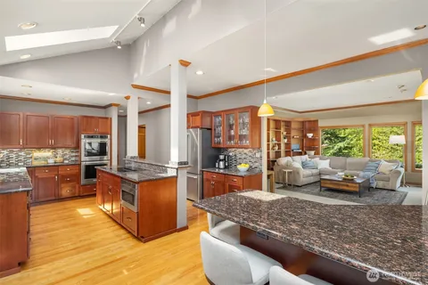 a large living room with stainless steel appliances granite countertop a couch wooden floor and a large window