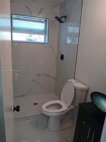 a white toilet sitting next to a shower