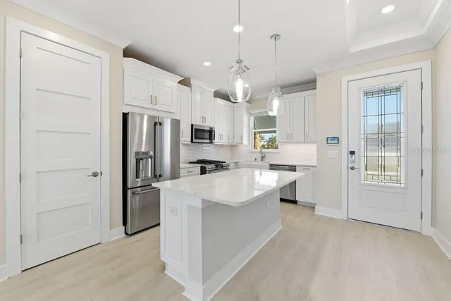 a large kitchen with stainless steel appliances kitchen island a stove a refrigerator and white cabinets