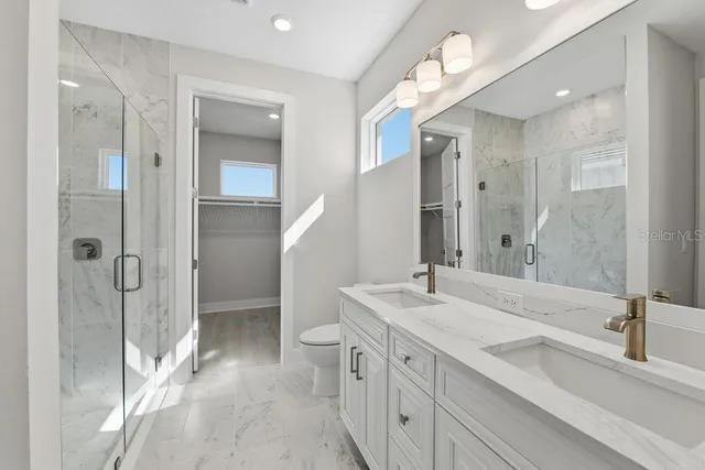 a bathroom with a double vanity sink mirror and shower