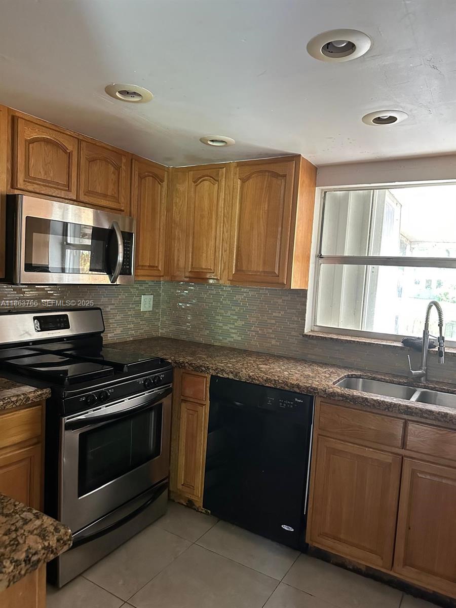 11208 Southwest 67th Terrace Miami, FL 33173 - Photo 31 of 33 a kitchen with granite countertop a stove top oven sink and cabinets