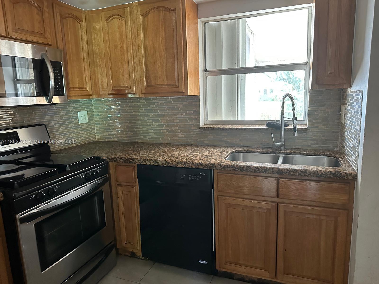11208 Southwest 67th Terrace Miami, FL 33173 - Photo 32 of 33 a kitchen with granite countertop a stove sink and cabinets