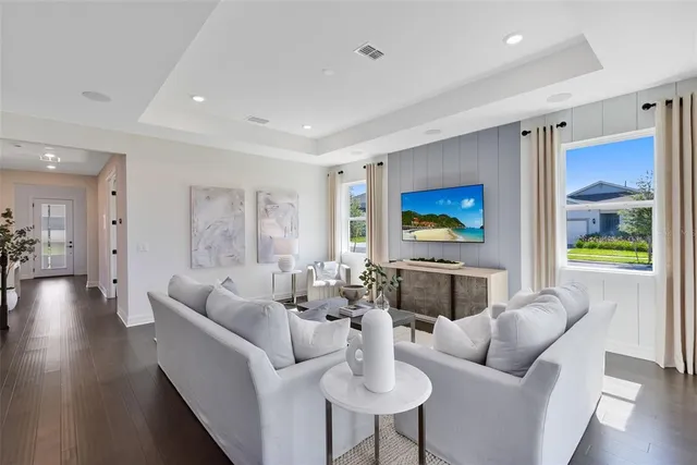 a living room with furniture white walls and kitchen view