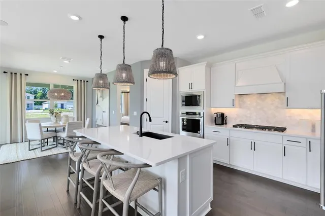 a large kitchen with white cabinets stainless steel appliances and a chandelier