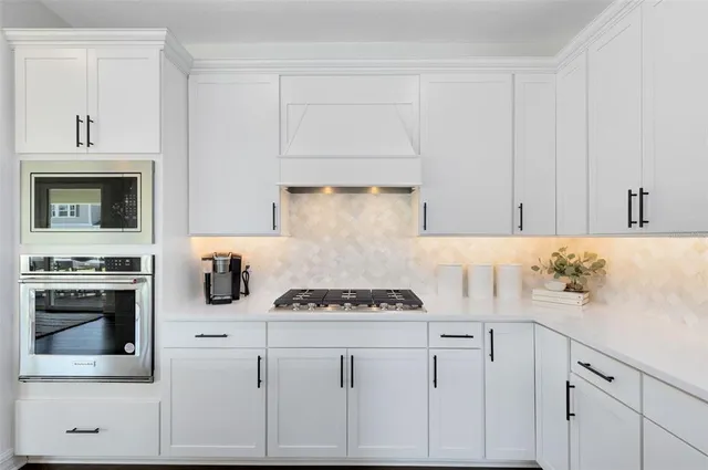 a kitchen with stainless steel appliances kitchen island granite countertop a dining table chairs and white cabinets