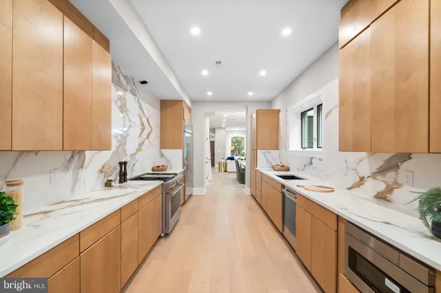 a large white kitchen with a large window and stainless steel appliances