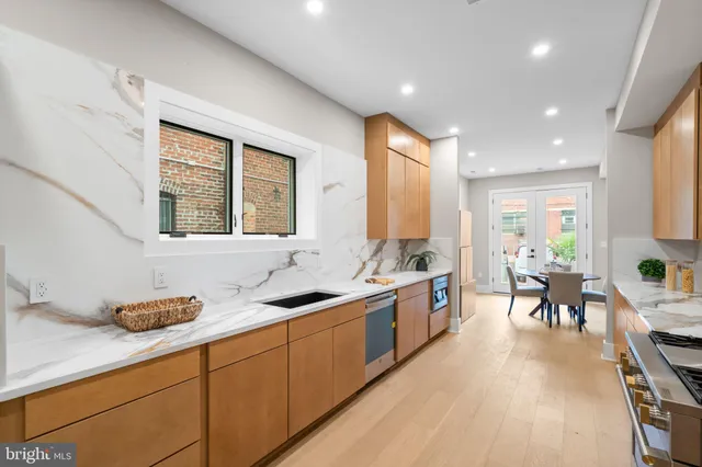 a large kitchen with stainless steel appliances a stove a sink a dining table and chairs