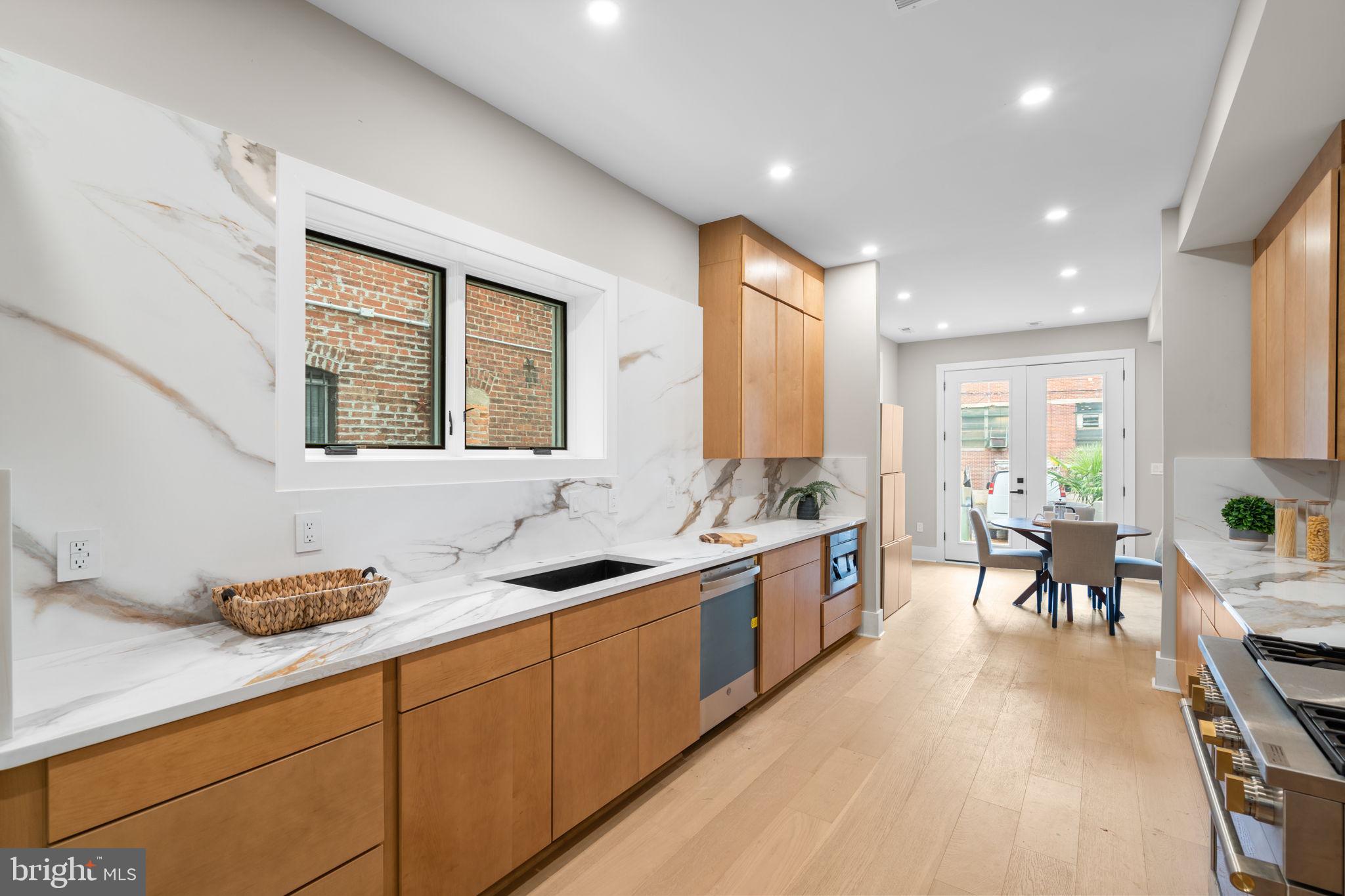 1816 13th Street Northwest Washington, DC 20009 - Photo 9 of 30 a large kitchen with stainless steel appliances a stove a sink a dining table and chairs