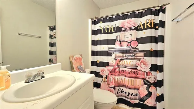 a bathroom with a sink a toilet and shower curtain