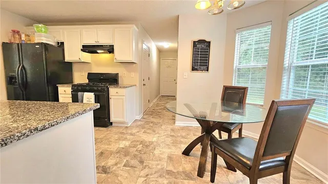 a kitchen with stainless steel appliances kitchen island granite countertop a table chairs and a refrigerator