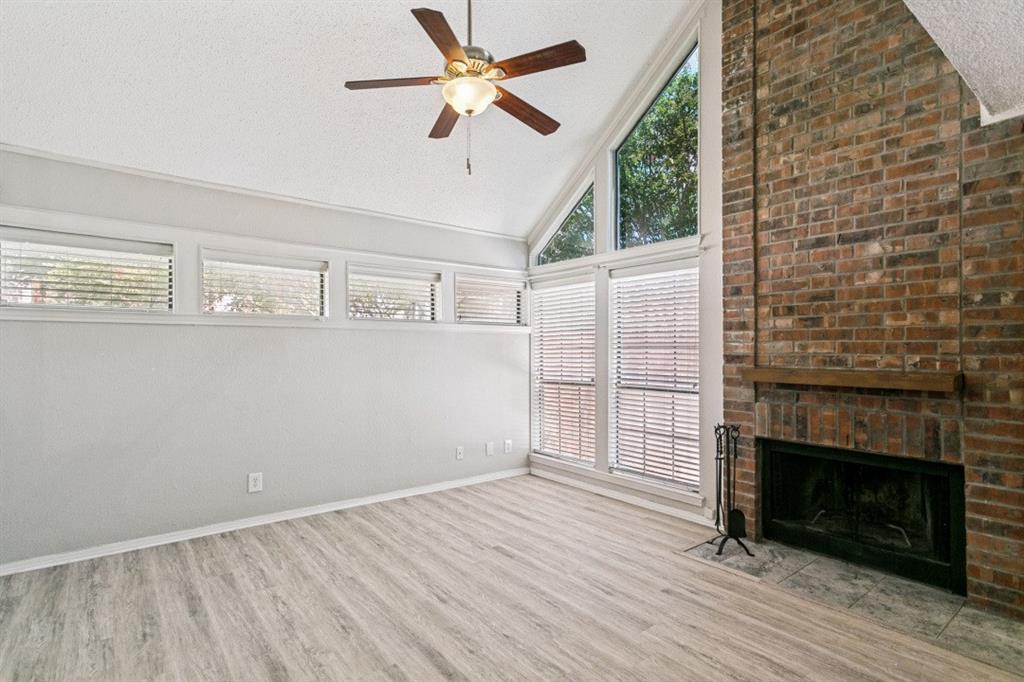 18240 Midway Road, Unit 905 Dallas, TX 75287 - Photo 12 of 29 Vaulted ceiling with a ceiling fan, brick fireplace with wood mantel, wood-finish flooring, and multiple windows