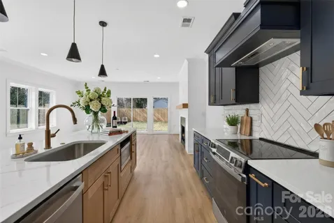 a kitchen with stainless steel appliances a sink a stove top oven a counter space and cabinets
