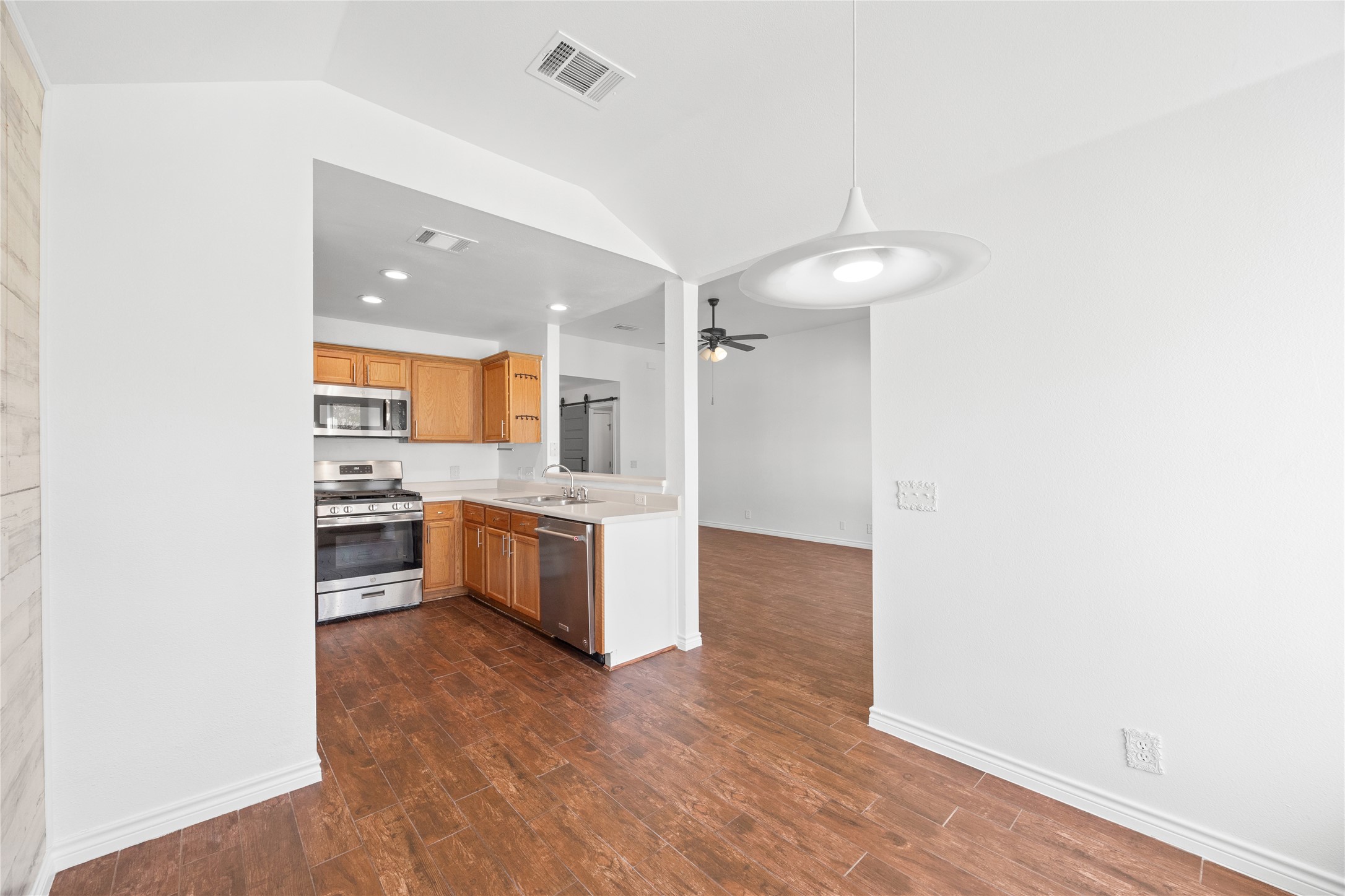 811 Lantana Lane Leander, TX 78641 - Photo 25 of 25 Kitchen with stainless steel appliances, light countertops, dark wood-style flooring, open floor plan, and hanging light fixtures