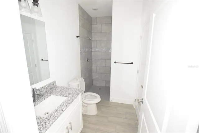 a bathroom with a granite countertop sink a toilet and shower