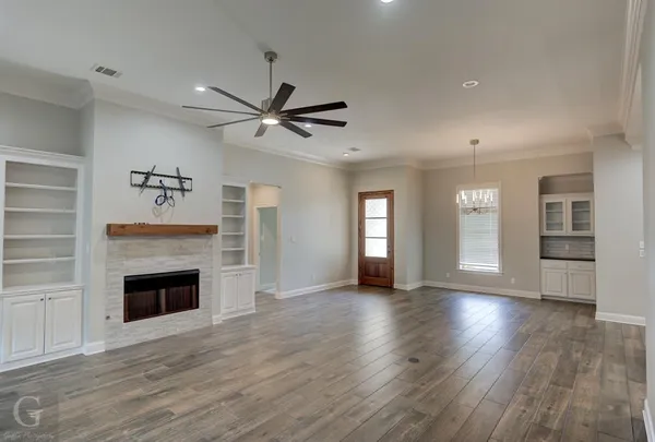 an empty room with wooden floor fireplace and windows
