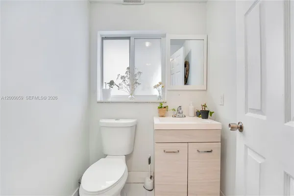 a bathroom with a toilet sink vanity and mirror