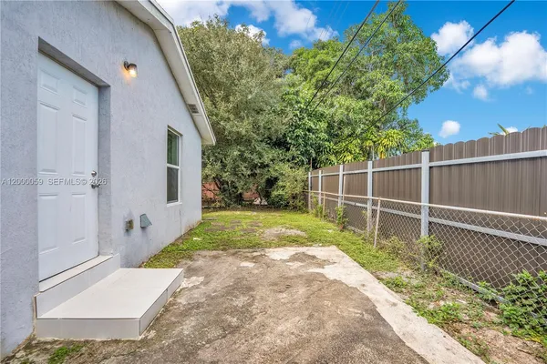 a backyard of a house with plants and large tree
