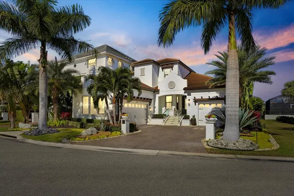 a view of a white house with a yard and palm trees